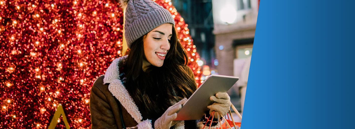 Woman on ipad with shopping bags in hand